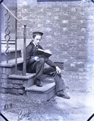 Glass negative of one of Baker sons sitting on steps.