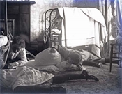 Glass negative of members of Baker family possibly sleeping on floor.