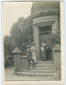 Photograph of entrance to house, with three figures.