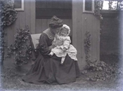 Glass negative of Pollie Baker with baby on knee.
