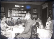 Glass negative of group, including Baker family members, sitting around table